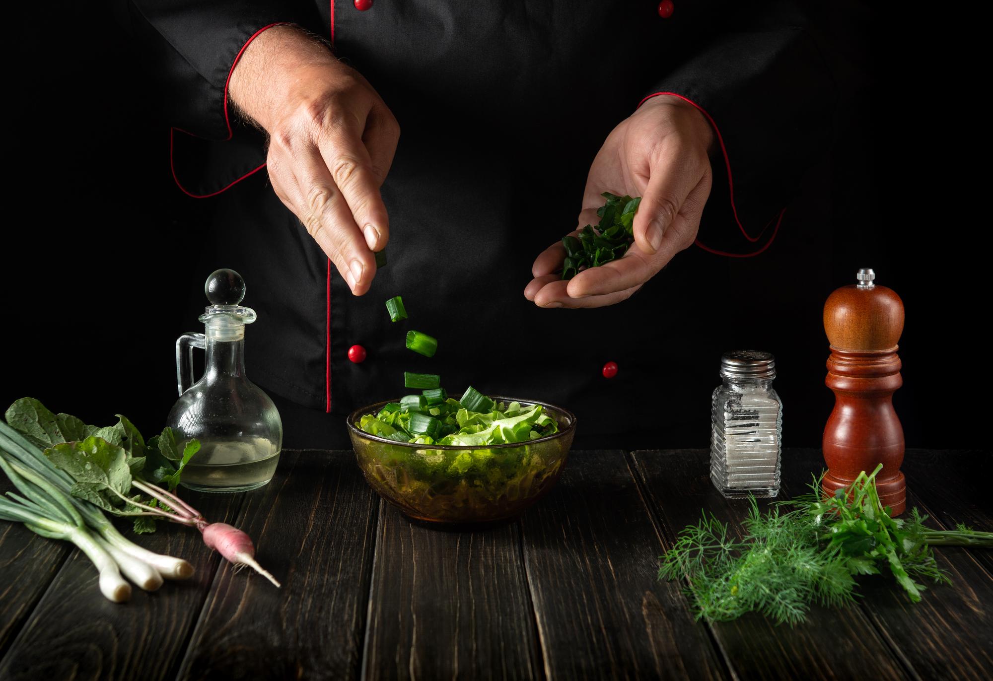 Chef arranging herbs on a wooden board