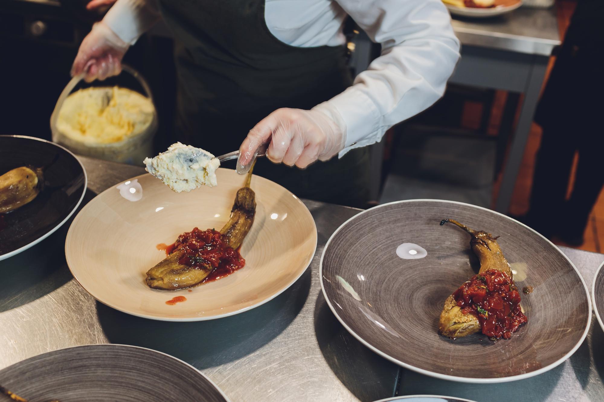 Instructor demonstrating a plated dish in a warm kitchen